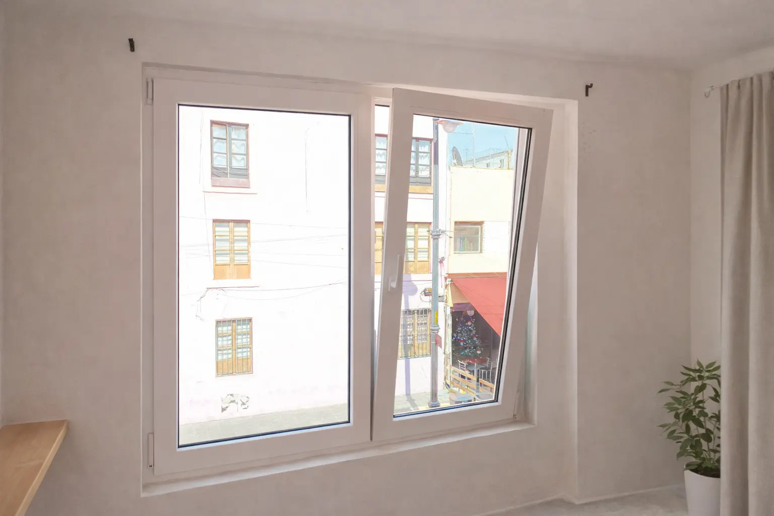 Ventana modular de PVC blanco con una hoja en posición oscilobatiente, integrada en una recámara con paredes claras y decoración minimalista, capturada en sitio de obra real.